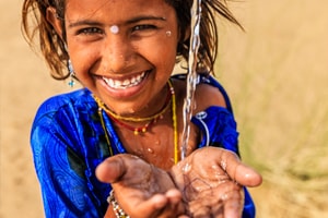 Happy child smiling into the camera because it has access to cheap drinking water now and does not have to suffer from water scarcity.