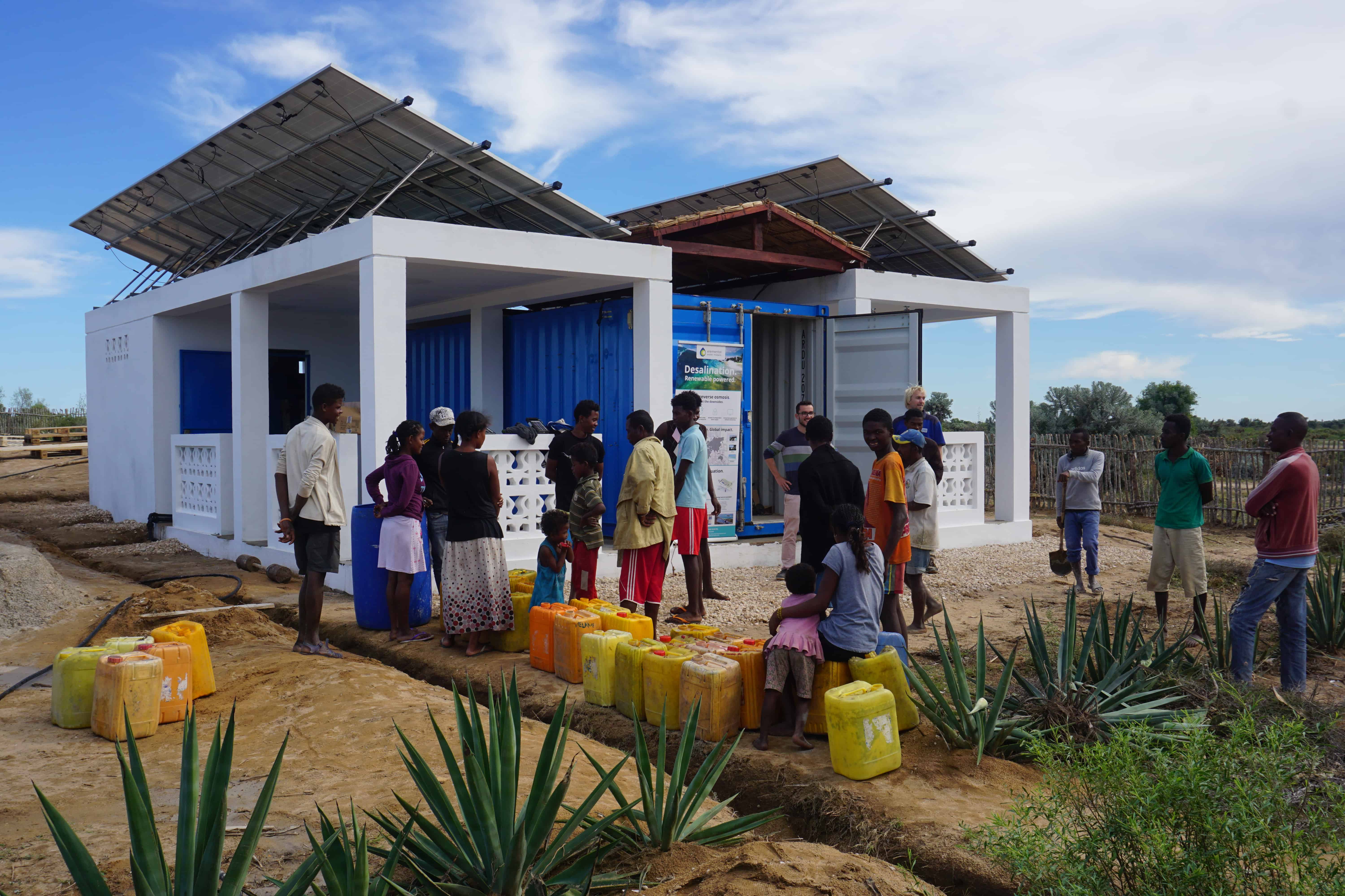 Villagers waiting for the desalination unit to be activated, building a queue in front of the container with their water tanks