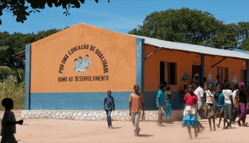 Our project in Mozambique, showing a basic school with children walking through the picture. This school is benefiting from access to affordable and clean drinking water.