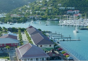 A harbour on the British Virgin Islands, with white boats in front of a small village of private properties anchoring in a peaceful bay with clear water
