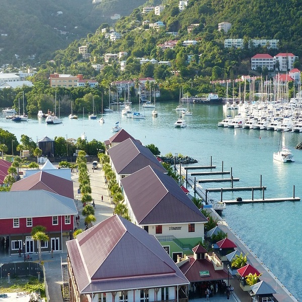 Harbour on the British Virgin Islands, with white boats in front of a small village of private properties anchoring in a peaceful bay with clear water