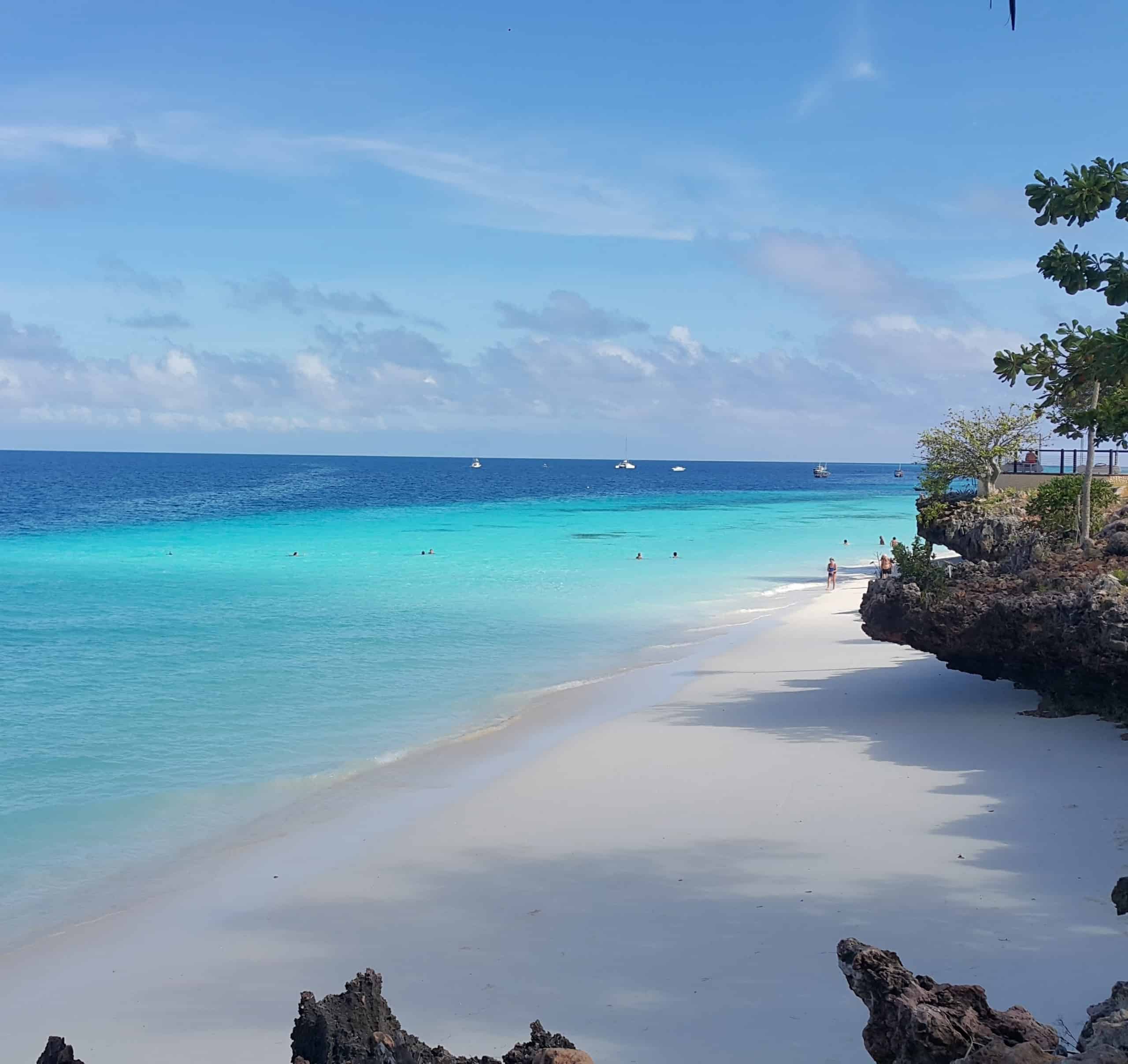 Narrow white beach with rocky cliffs in Tanzania, next to the off grid solar purification machine that was manufactured by elemental water makers to provide clean desalinated water.