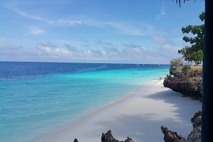 White beach with rocky cliffs in Tanzania, next to the off grid solar purification machine that was manufactured by elemental water makers to provide clean desalinated water.