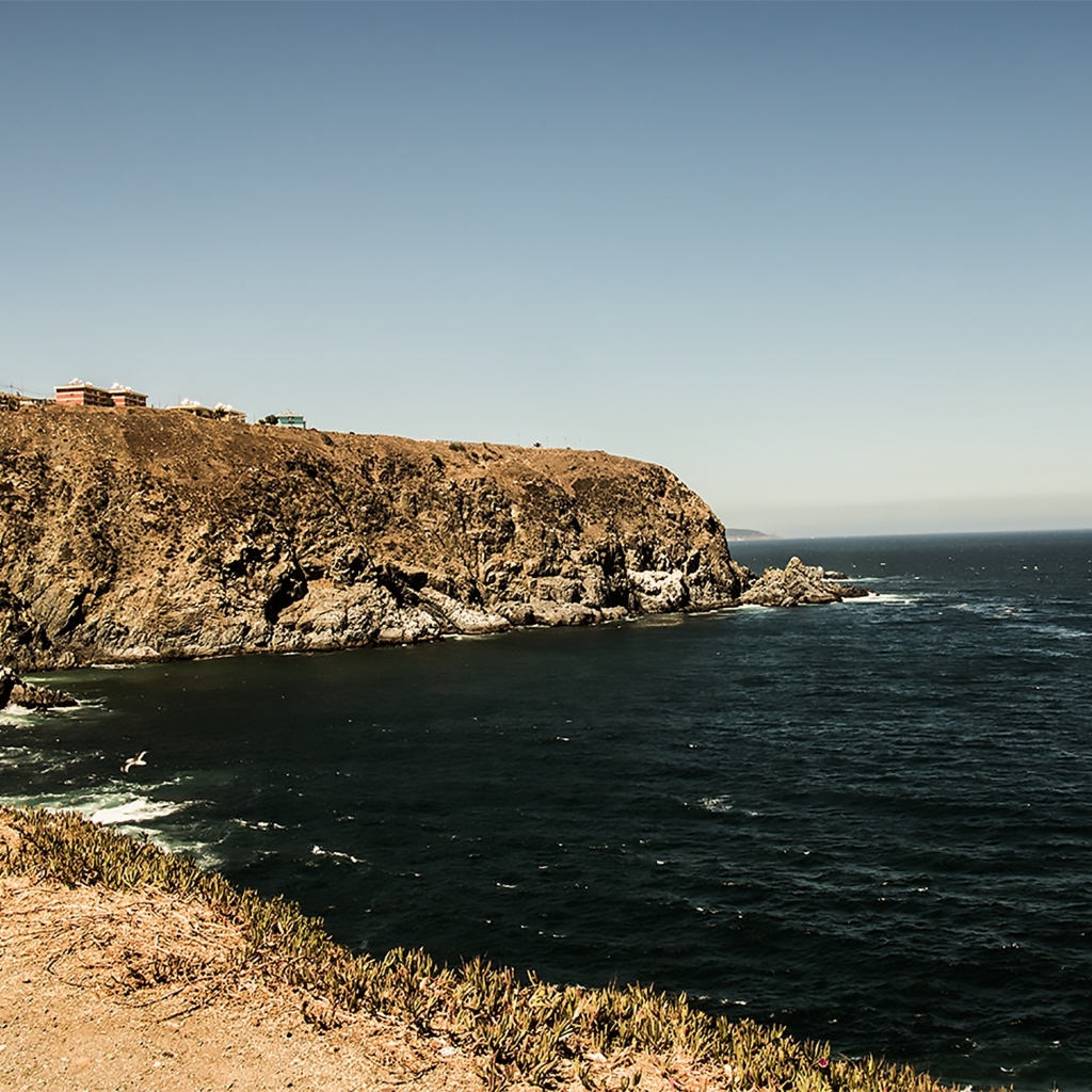 Rocky desert-like coastline in Chile with the waves rolling into the bay and shaping the coast.