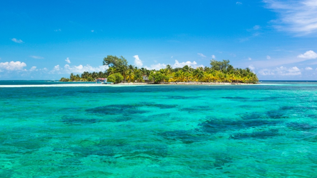 Villa in Belize with a small pier leading into the water and solar panels on the roof, which are providing green energy for the reverse osmosis desalination process.